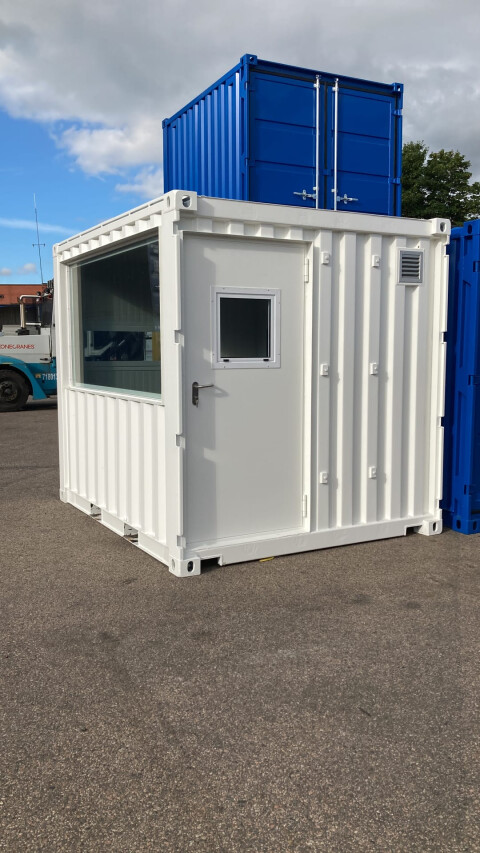 Witte zeecontainer omgebouwd tot compacte kantoorunit met raam en deur op buitenterrein