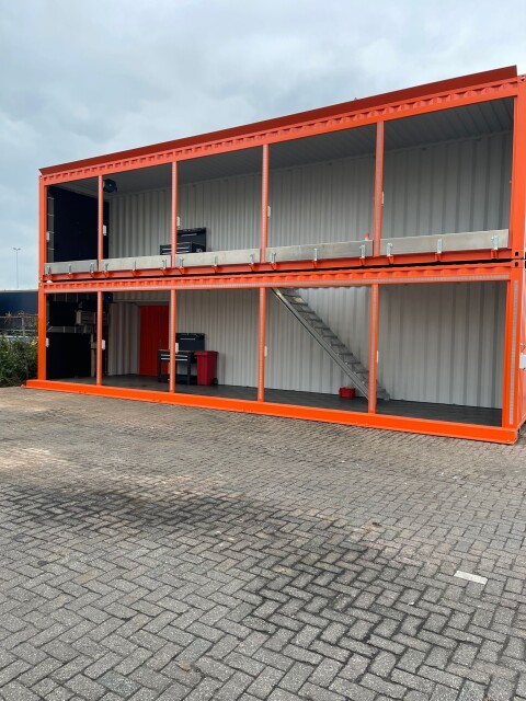 Twee oranje zeecontainers gestapeld tot dubbele werkruimte met trap en open voorzijde bij Van Doorn Container Modifications