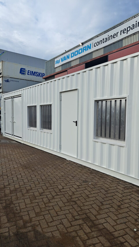 Witte zeecontainer omgebouwd tot kantoorunit met ramen en deur op het terrein van Van Doorn Container Modifications
